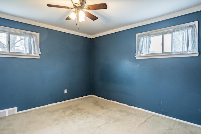 carpeted empty room with a ceiling fan, visible vents, and baseboards