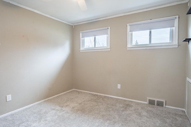 spare room featuring carpet floors, ornamental molding, visible vents, and baseboards