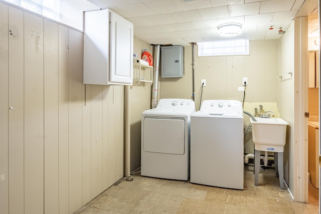 laundry room featuring cabinet space, electric panel, wood walls, light floors, and separate washer and dryer