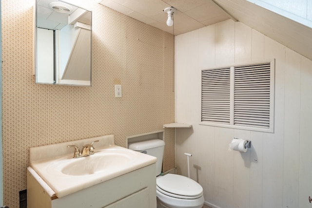 bathroom featuring toilet, wallpapered walls, and vanity