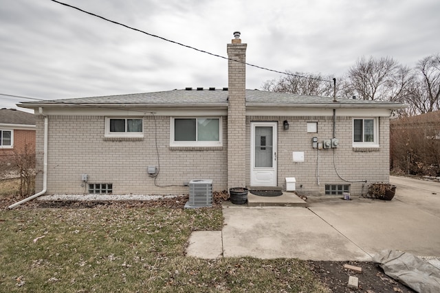 back of property featuring central air condition unit, brick siding, a shingled roof, a chimney, and a patio area