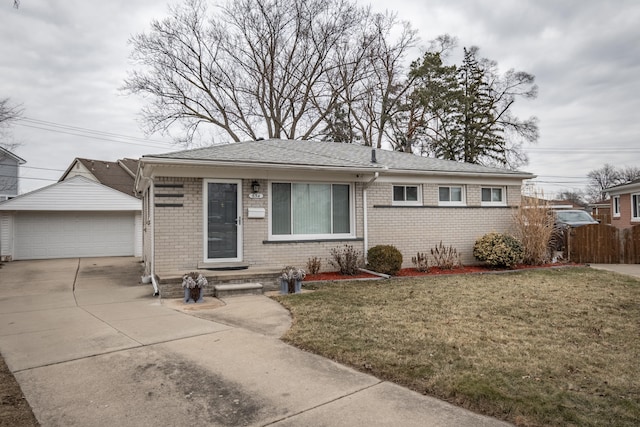 view of front of home featuring a detached garage, fence, a front lawn, and brick siding