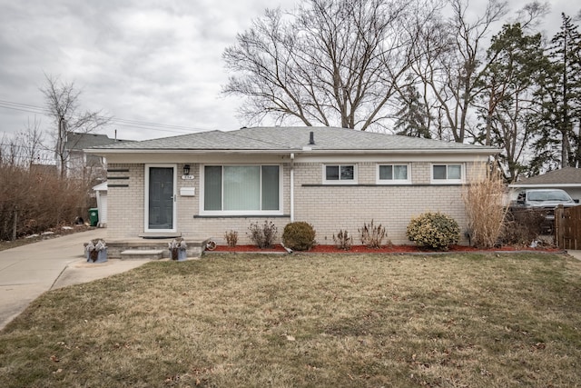 view of front facade featuring brick siding, a front yard, and fence