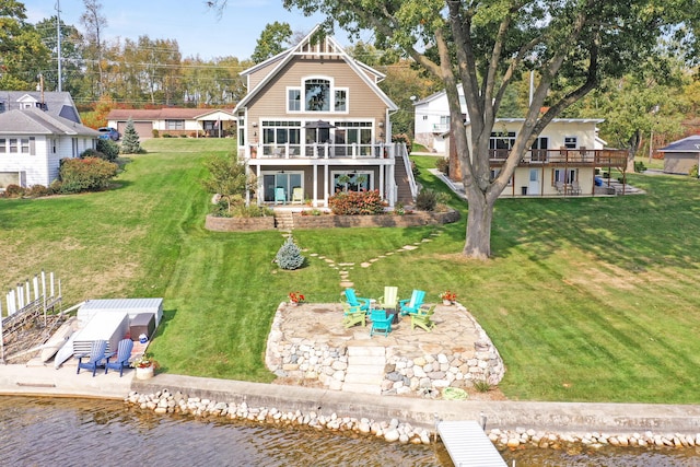 back of property with a patio area, an outdoor fire pit, a lawn, and a deck with water view