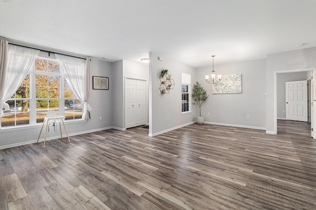 interior space featuring a chandelier, dark wood-style flooring, and baseboards