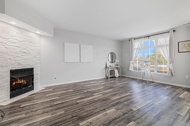 unfurnished living room featuring a fireplace, baseboards, and wood finished floors