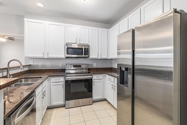 kitchen featuring light tile patterned floors, stainless steel appliances, white cabinets, a sink, and ceiling fan