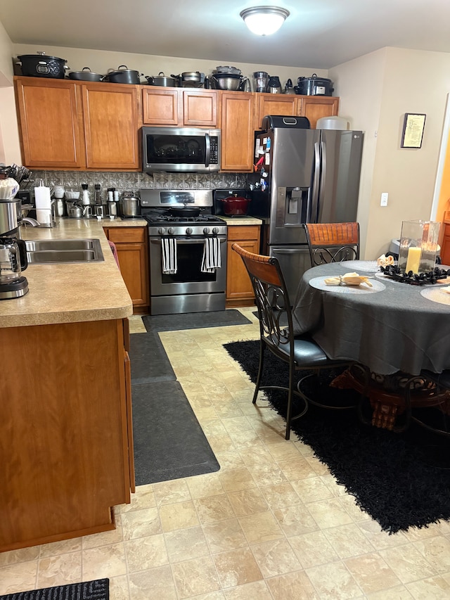 kitchen featuring a sink, stainless steel appliances, tasteful backsplash, and light countertops