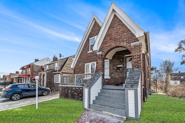 view of front of house with a front yard, covered porch, and brick siding