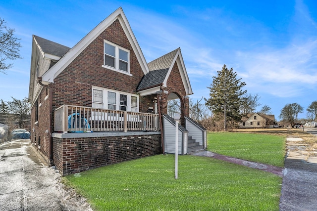 view of front of home with brick siding, driveway, a shingled roof, and a front yard