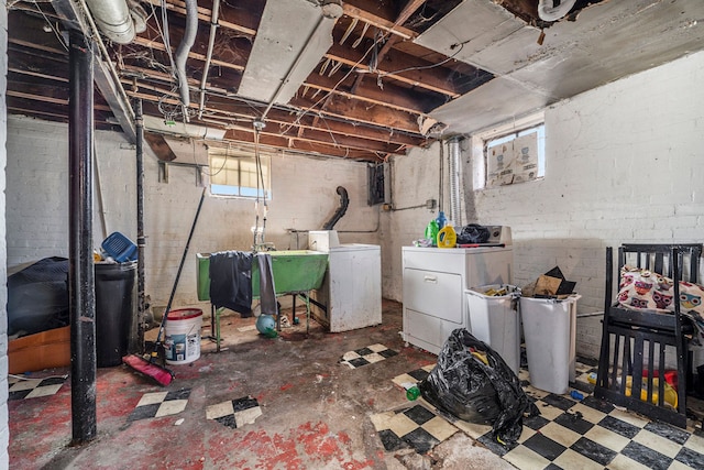 basement featuring tile patterned floors, washing machine and dryer, and a sink