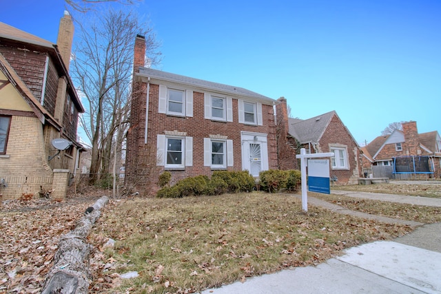 view of front facade featuring a trampoline, brick siding, and a chimney