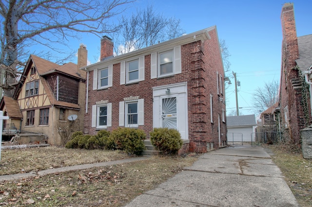 view of front of home featuring an outbuilding, brick siding, a chimney, and a detached garage