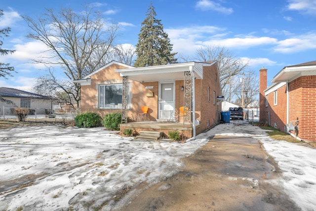 view of front of property featuring covered porch, brick siding, and driveway