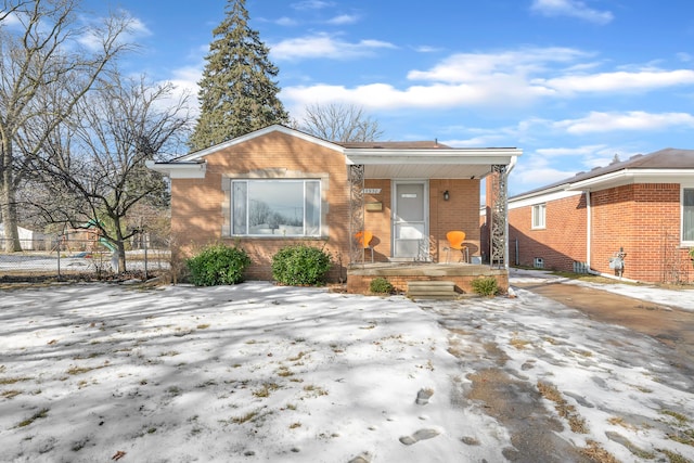 view of front of property with fence, a porch, and brick siding