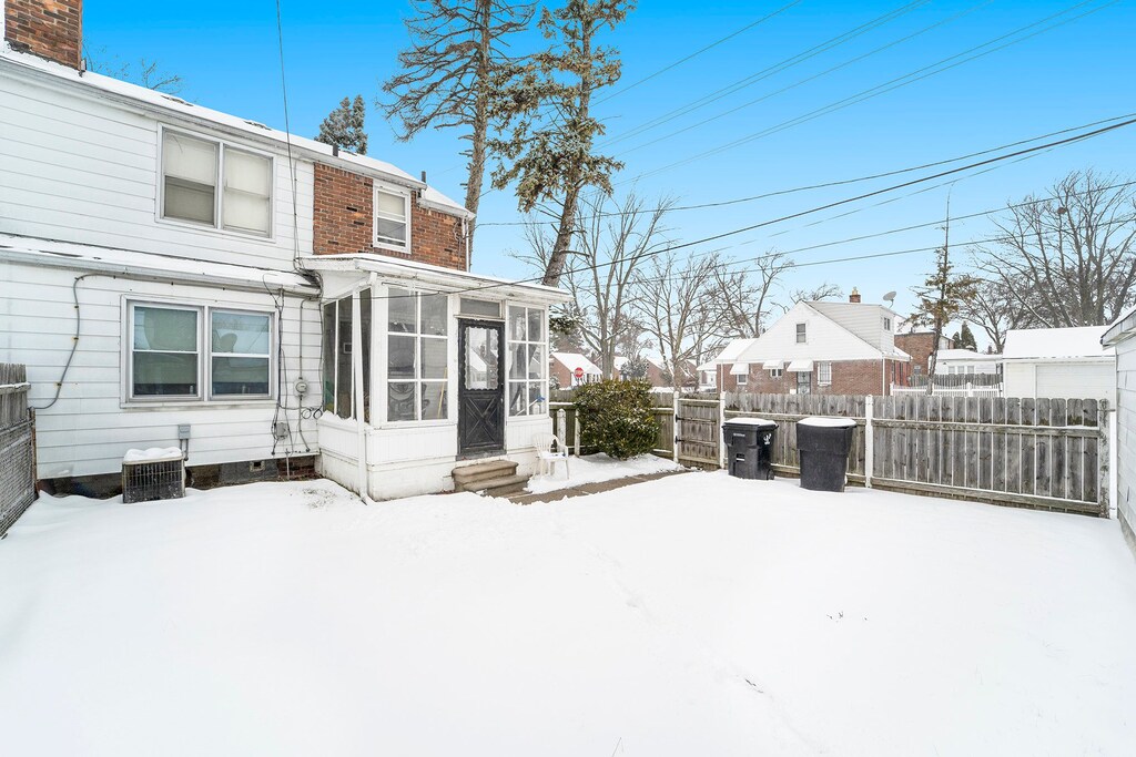 20248 Regent Dr, Detroit, MI 48205 - snow covered property with fence and a sunroom