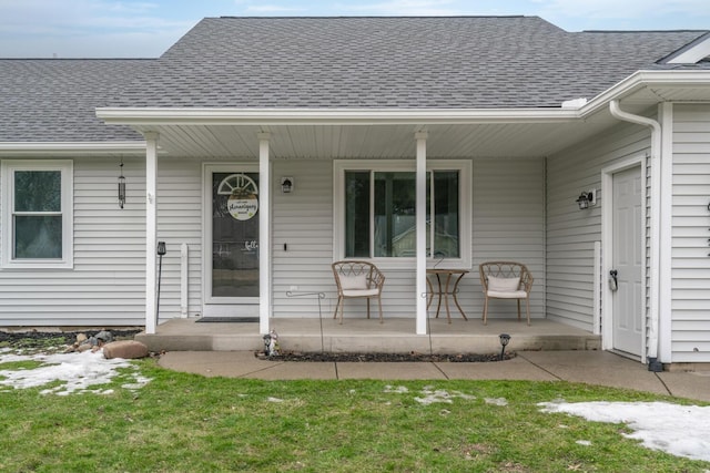 doorway to property with a porch and roof with shingles