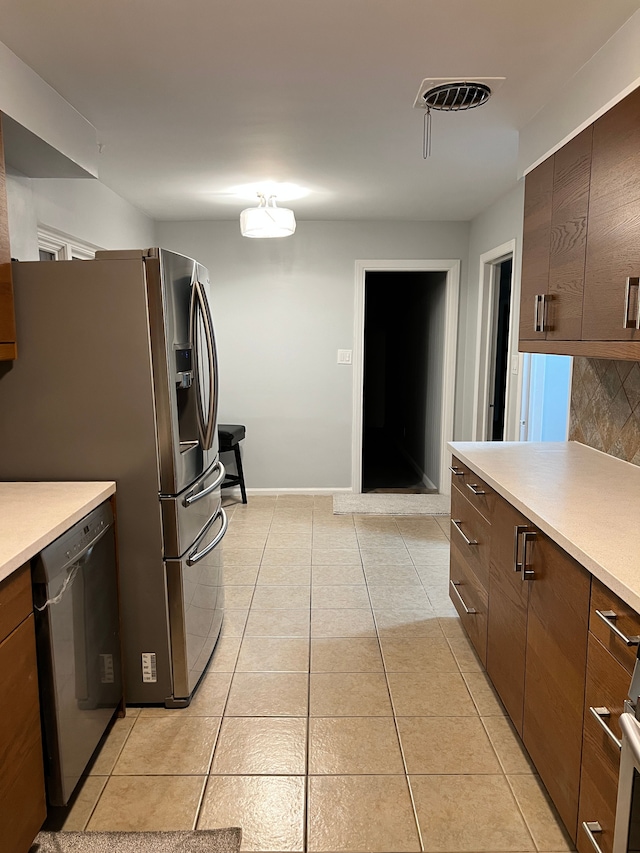 kitchen with stainless steel appliances, light countertops, visible vents, decorative backsplash, and light tile patterned flooring