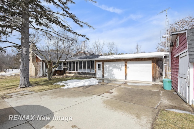 view of front of house with driveway, a sunroom, and an attached garage