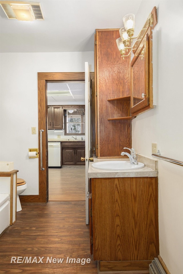 bathroom with a baseboard radiator, visible vents, toilet, vanity, and wood finished floors