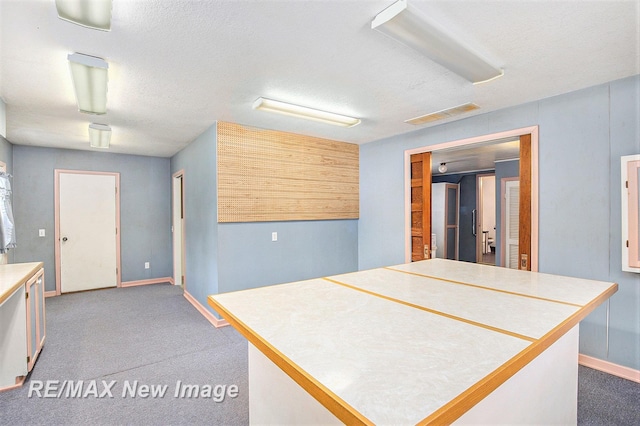 kitchen with a textured ceiling, visible vents, light countertops, and carpet flooring