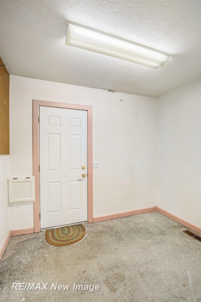 empty room featuring a textured ceiling, visible vents, and baseboards