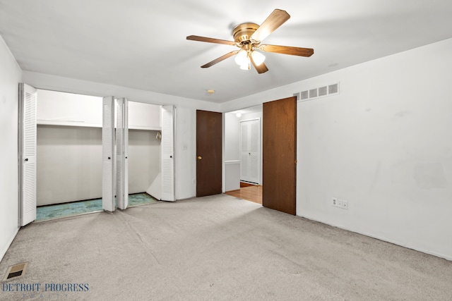 unfurnished bedroom with ceiling fan, carpet floors, two closets, and visible vents