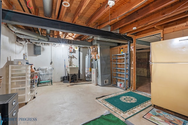 unfinished basement with freestanding refrigerator, water heater, a sink, and heating unit