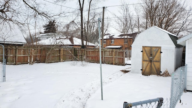 yard layered in snow featuring fence, an outdoor structure, and a shed