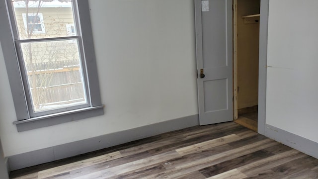 unfurnished bedroom featuring multiple windows, baseboards, and wood finished floors