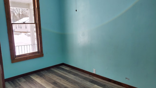 empty room with baseboards and dark wood-type flooring