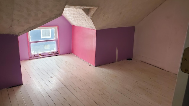 additional living space featuring light wood-style flooring and vaulted ceiling