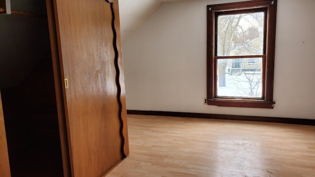 additional living space with a healthy amount of sunlight, light wood-style flooring, and baseboards