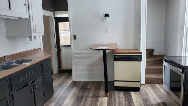 kitchen featuring white dishwasher, light wood-style flooring, electric range, a sink, and white cabinets