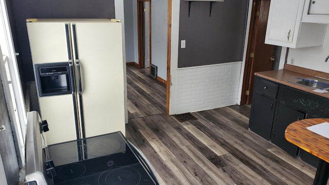 kitchen with visible vents, white cabinets, dark wood-type flooring, white fridge with ice dispenser, and a sink