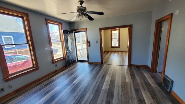 interior space featuring baseboards, visible vents, ceiling fan, and wood finished floors