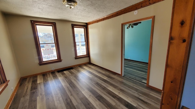 empty room featuring visible vents, a textured ceiling, baseboards, and wood finished floors