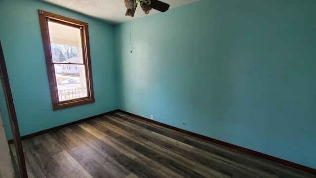 unfurnished room with a ceiling fan, baseboards, and dark wood-style flooring