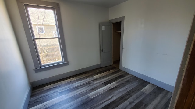 spare room featuring dark wood-style floors and baseboards