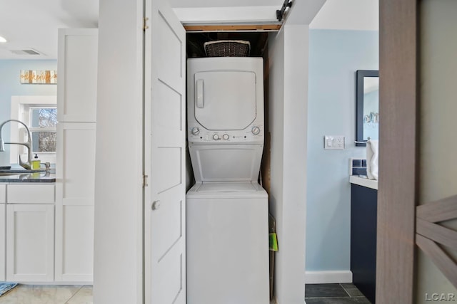 laundry room with visible vents, a sink, stacked washing maching and dryer, laundry area, and baseboards