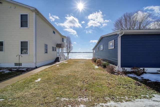 view of property exterior with a water view and a lawn