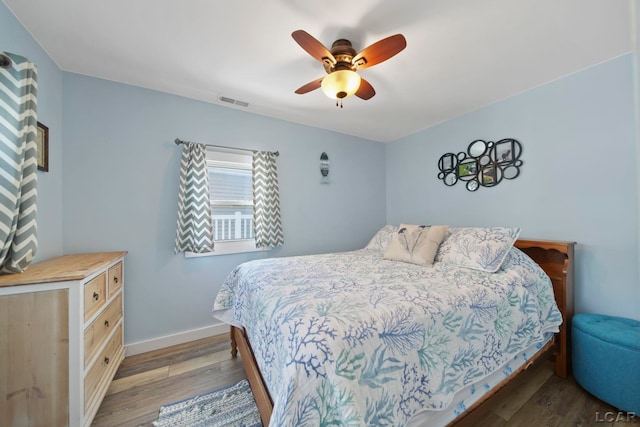 bedroom featuring visible vents, wood finished floors, a ceiling fan, and baseboards