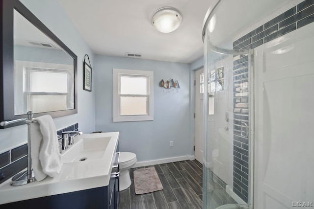 bathroom featuring toilet, a stall shower, wood tiled floor, and baseboards