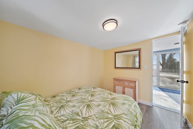 bedroom featuring access to exterior, baseboards, and wood finished floors