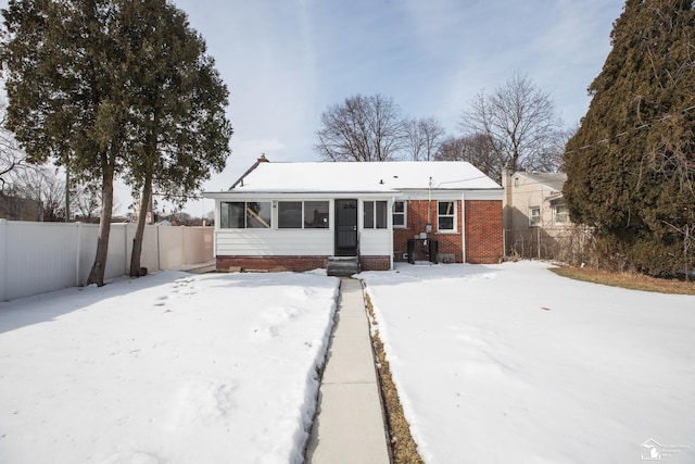 view of front facade featuring fence private yard, a sunroom, and brick siding