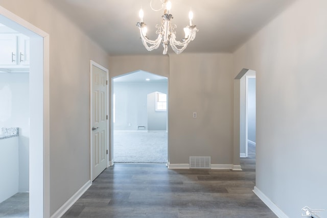 interior space with arched walkways, visible vents, an inviting chandelier, wood finished floors, and baseboards