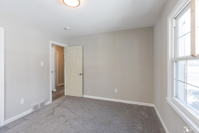 carpeted spare room featuring visible vents and baseboards