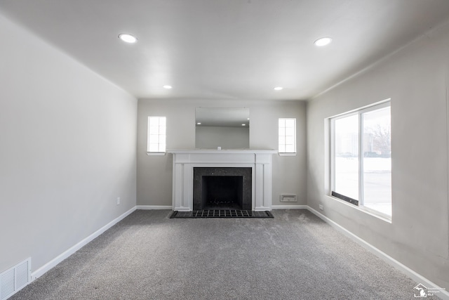 unfurnished living room with a fireplace with flush hearth, visible vents, dark colored carpet, and baseboards