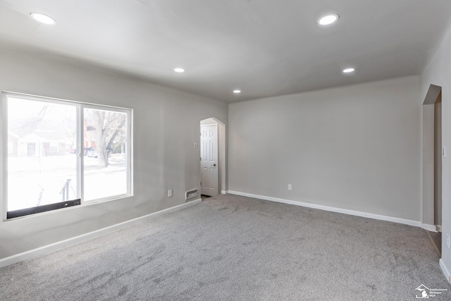 empty room featuring carpet floors, recessed lighting, arched walkways, and baseboards