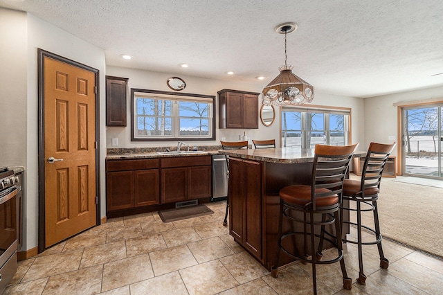 kitchen featuring a center island, a sink, dark brown cabinetry, and a kitchen breakfast bar